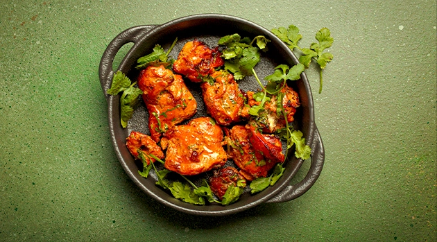 Delicious tandoori chicken garnished with herbs, served as part of the best Indian food Singapore experience.