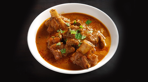 Spicy Indian mutton curry with bones and cilantro, a true taste of the best Indian food experience.
